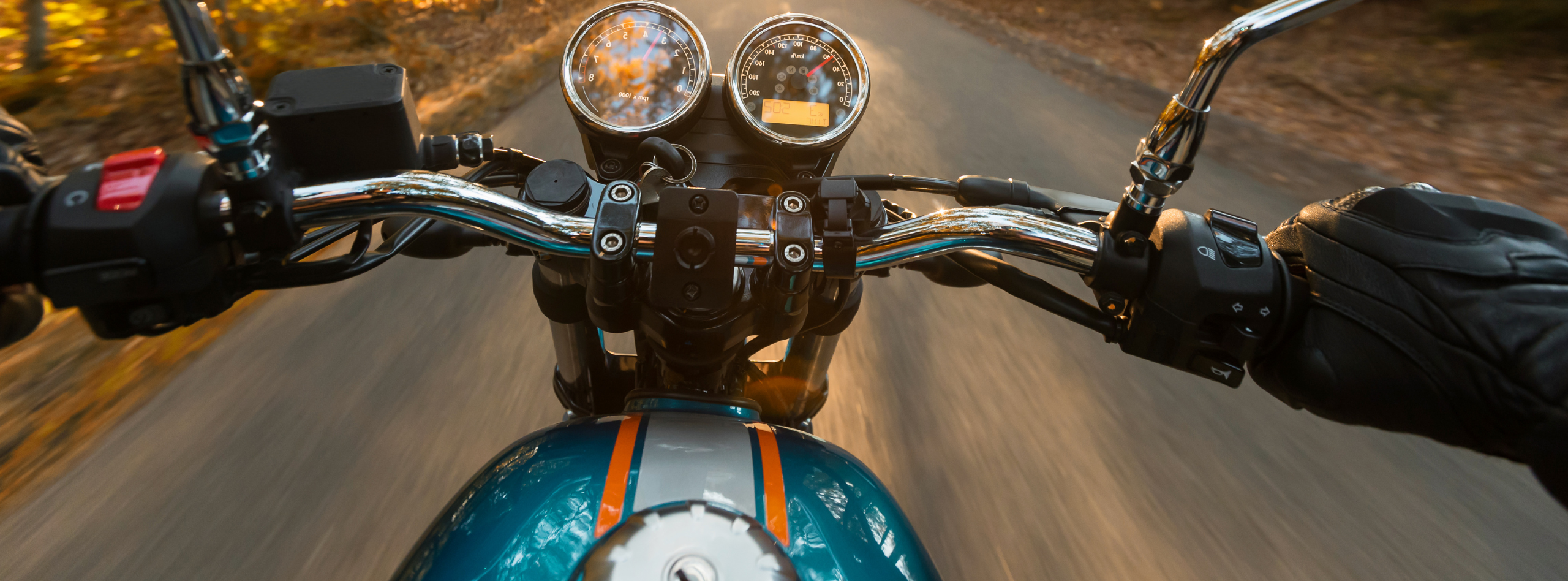 Motorcyclist riding on a scenic road, hands on the handlebars and speed gauges visible, representing the need for reliable motorcycle insurance from Westland Insurance.