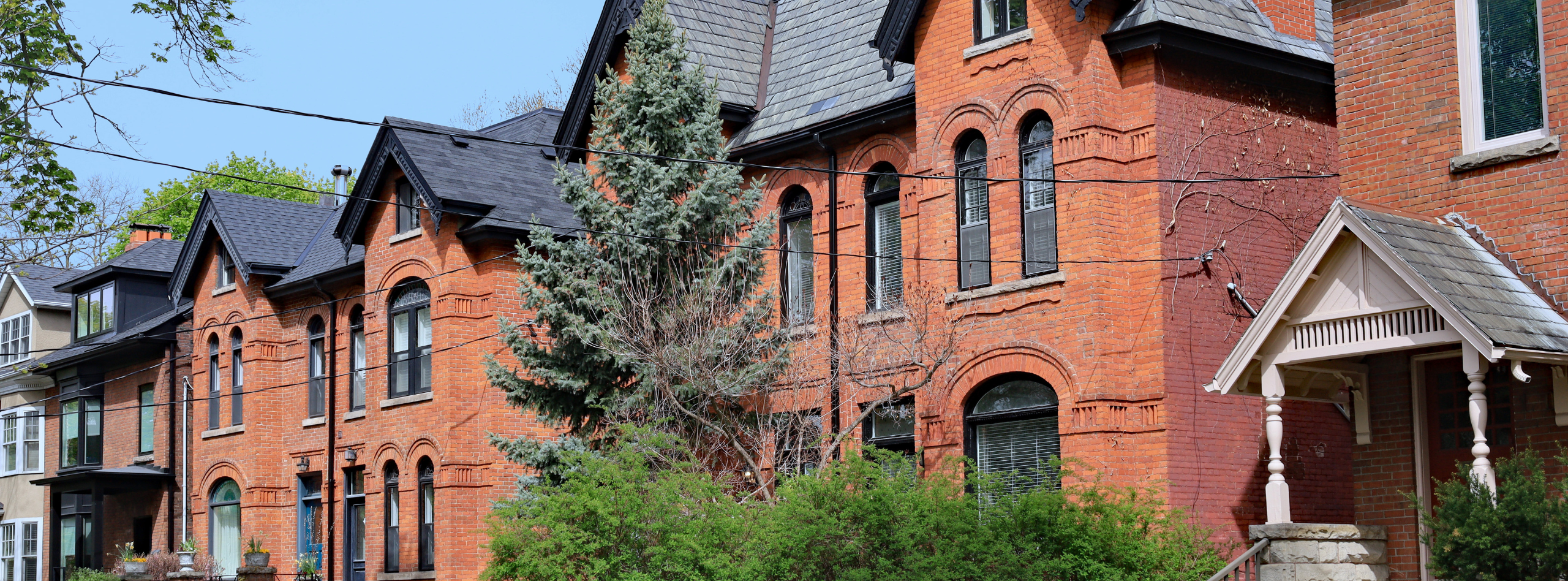 Historic brick rental homes in Canada, surrounded by trees and greenery, representing properties protected with rental property insurance from Westland Insurance.